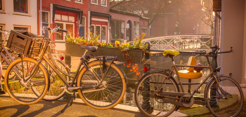 Fietsen langs een sfeervol Gouds grachtenpand met een geel zadel in het ochtendlicht.