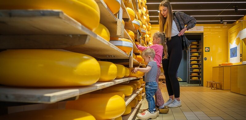 Moeder en kinderen ontdekken grote ronde Goudse kazen tijdens een interactief bezoek aan de Gouda Cheese Experience.