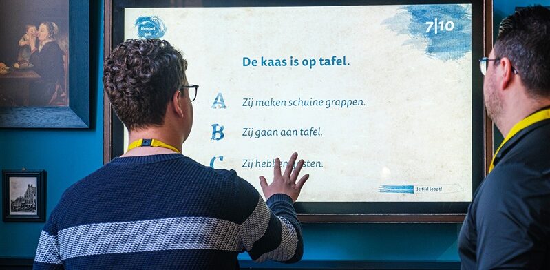 Twee bezoekers doen een interactieve taalquiz over kaasgezegdes bij de Gouda Cheese Experience.