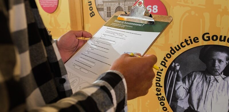 Bezoeker vult een kaasquiz in op een clipboard tijdens een interactieve opdracht bij de Gouda Cheese Experience.